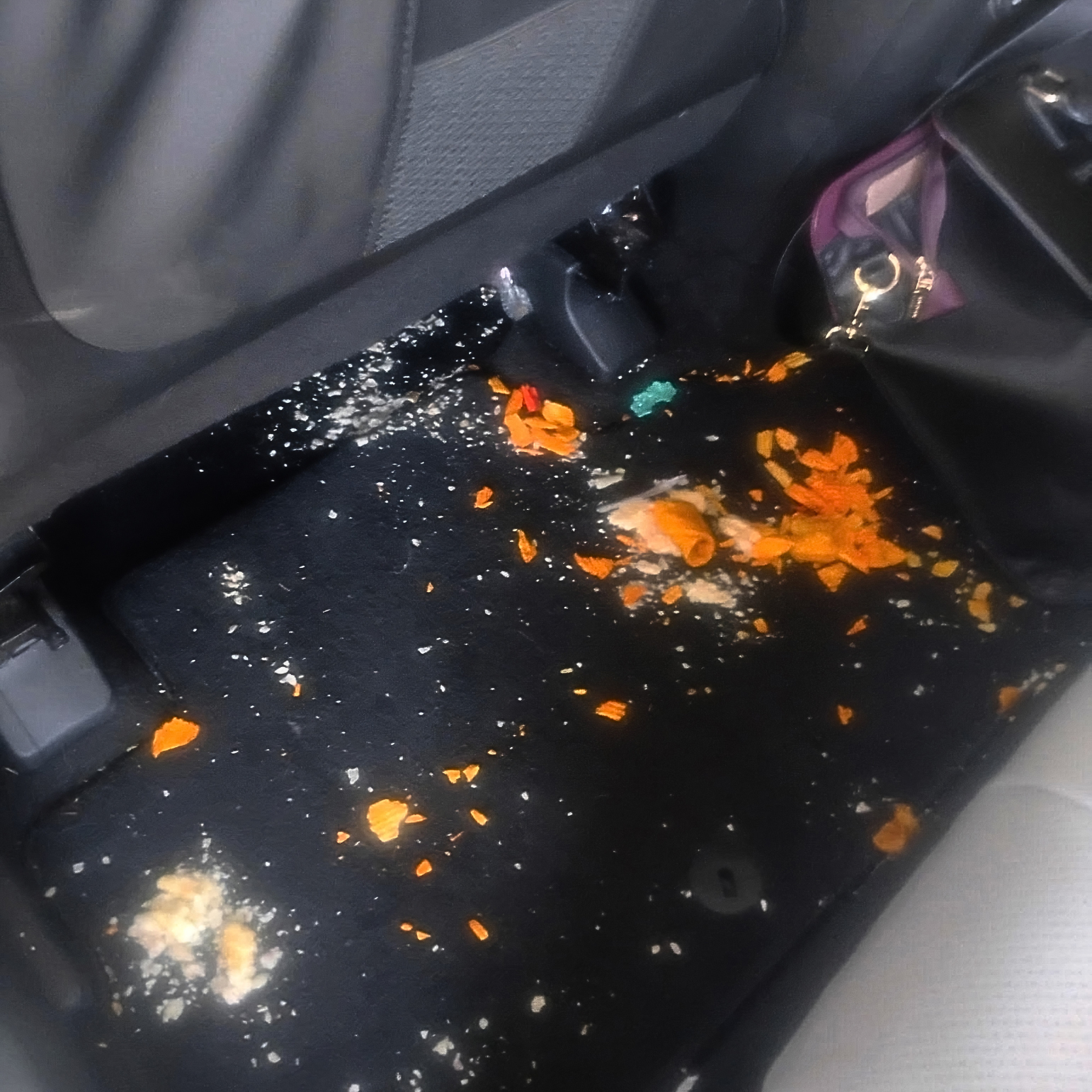 Car floor mat covered in crumbs and debris before detailing